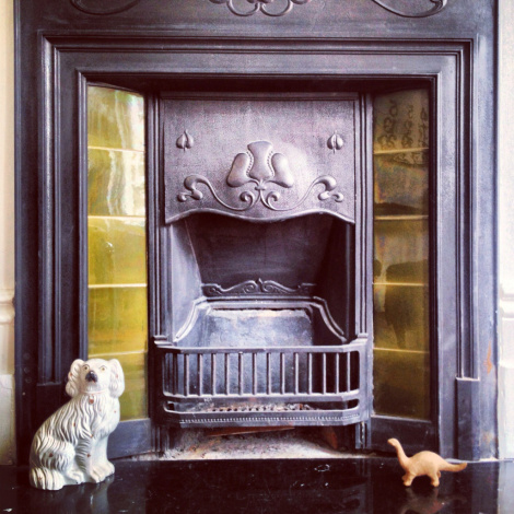 Fireplace with miniature dinosaur and Staffordshire dog