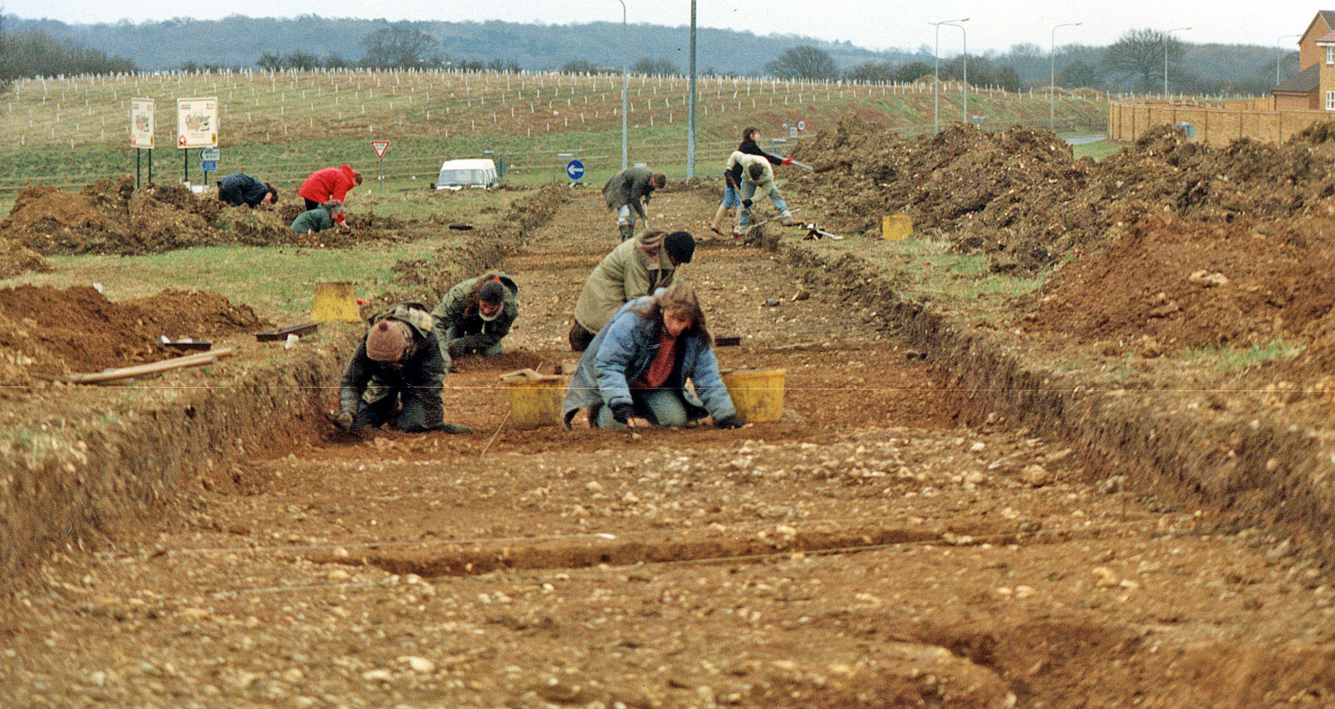 archaeologists in a shallow trench